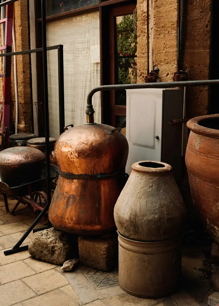 Taş bir avluda eski bir bakır imbik ve toprak küpler