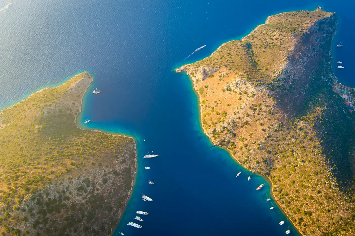 Havadan bakıldığında iki yarımada arasında koyu mavi bir deniz ve demirli tekneler