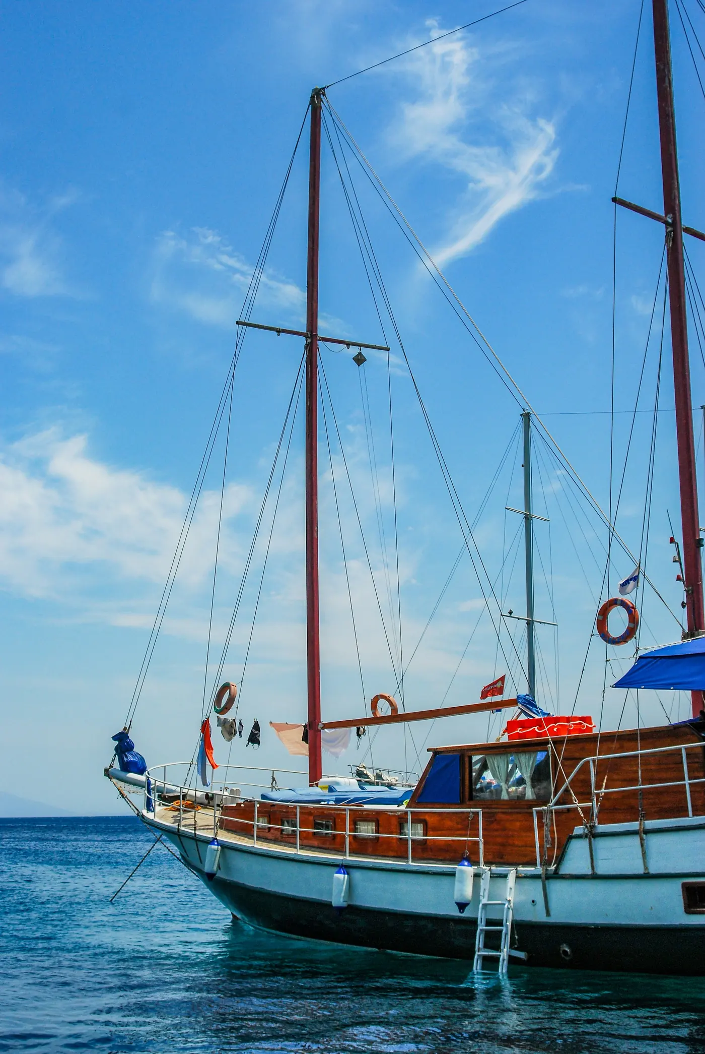 Açık denizde demirli, beyaz gövdeli iki direkli bir gulet