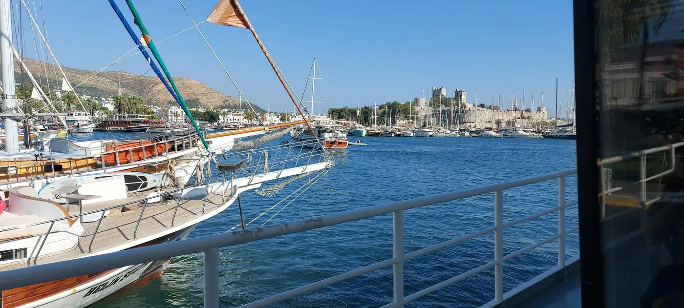 Bodrum limanında bağlı tekneler, uzakta taş bir kale