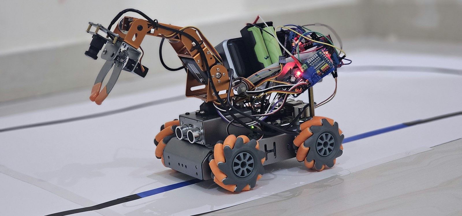 Çizgili bir pistte tutucu kollu, turuncu tekerlekli bir robot