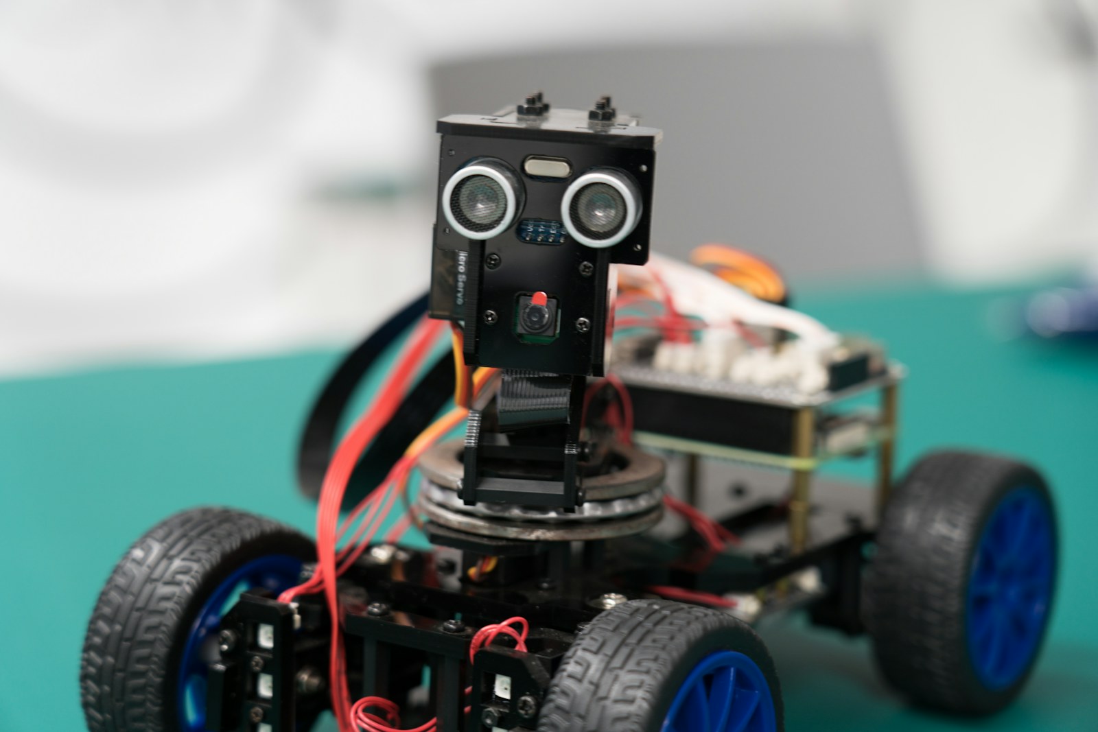 Ultrasonik mesafe sensörü takılı, mavi tekerlekli küçük bir robot