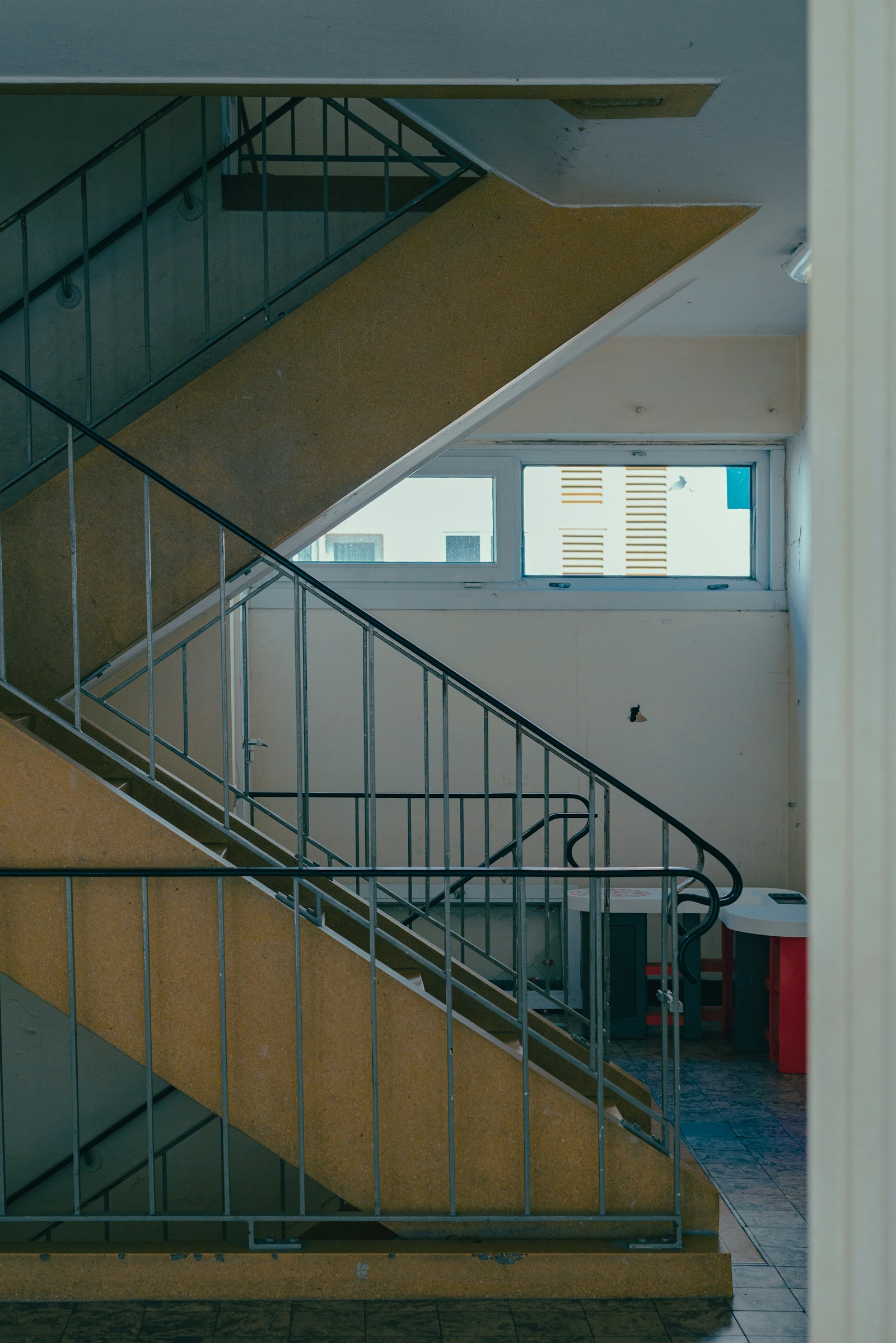 Metal korkuluklu merdivenleri ve pencereli sahanlığı olan bir apartman merdiven boşluğu
