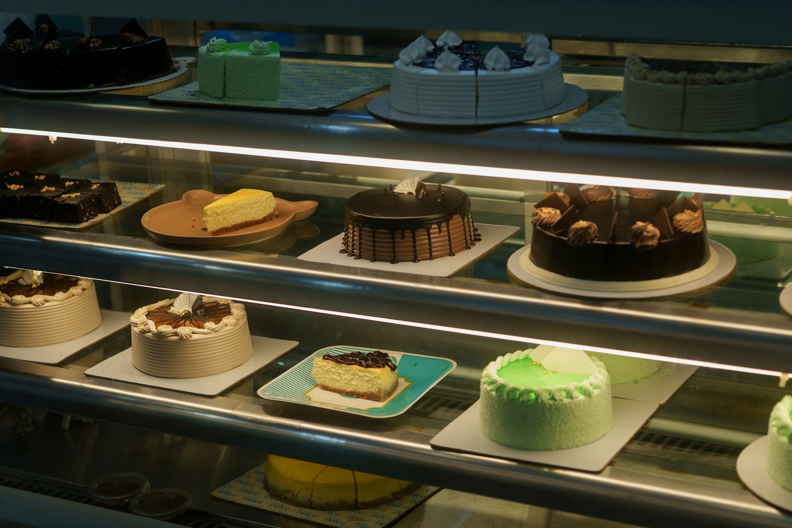 Işıklı cam bir vitrinin raflarında dizili bütün pastalar ve cheesecake dilimleri