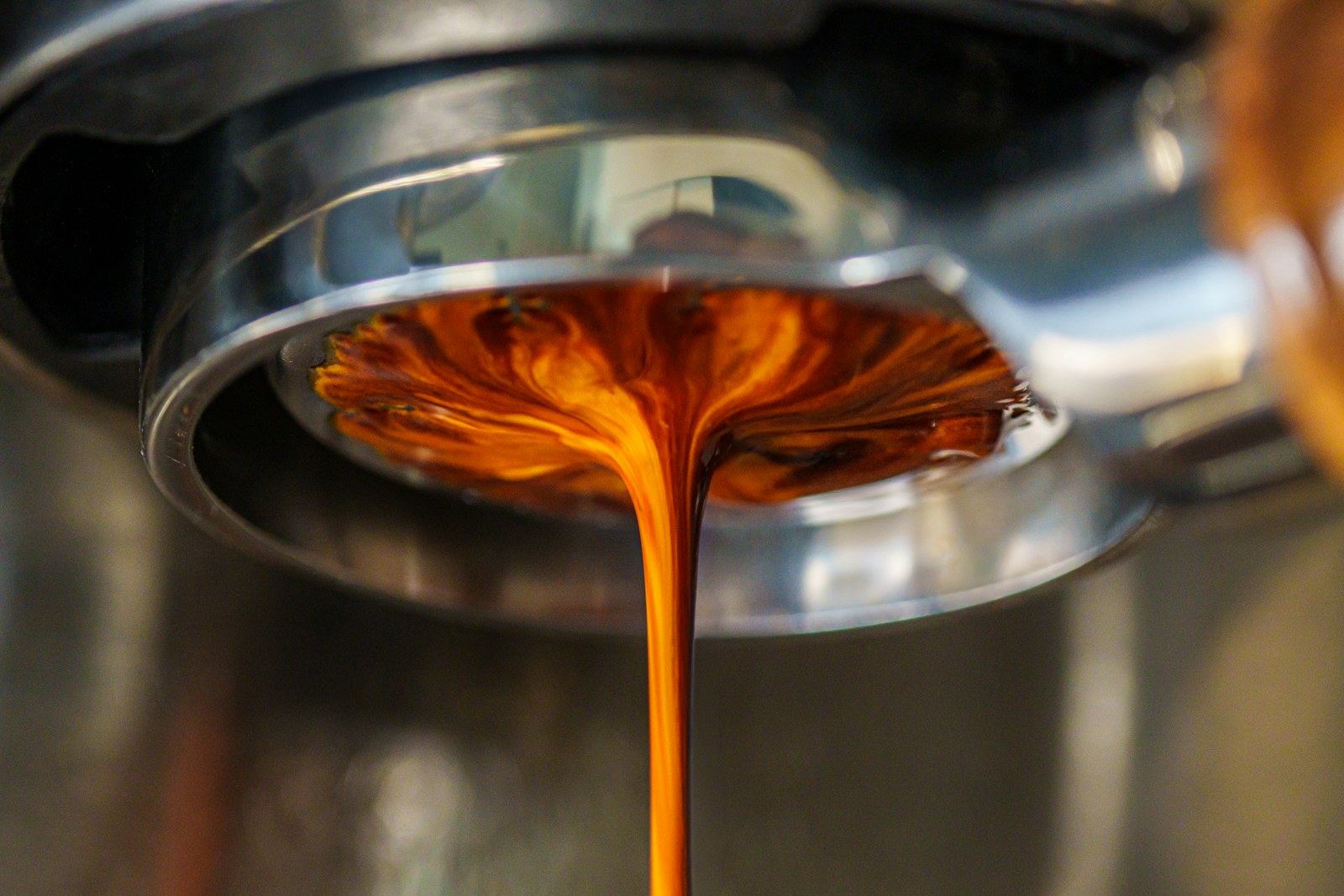 Bir kahve makinesinin portafiltresinden, altındaki fincana ince bir akışla damlayan espresso