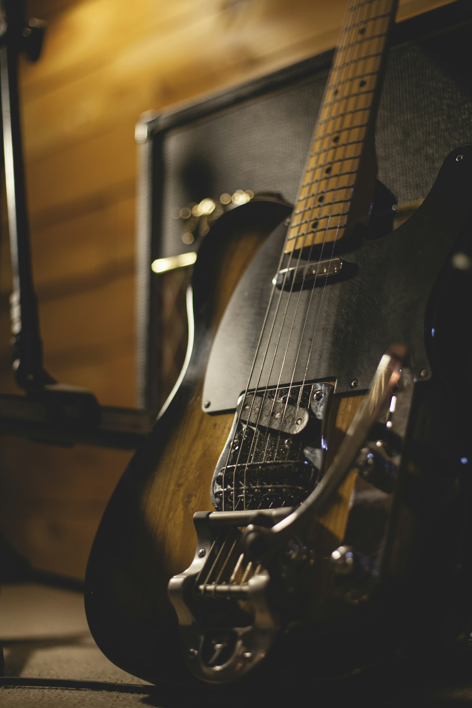 Ahşap kaplı bir odada amfiye yaslanmış bir elektro gitar