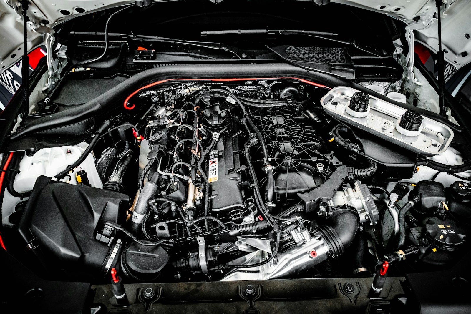 Kaputu açık bir aracın hortumlar ve kablolarla dolu motor bölmesi