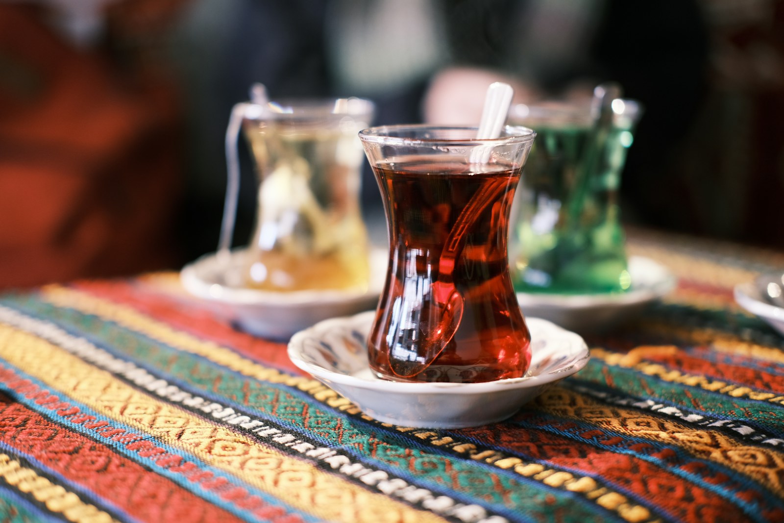 Renkli dokuma bir örtünün üstünde ince belli bardaklarda çay