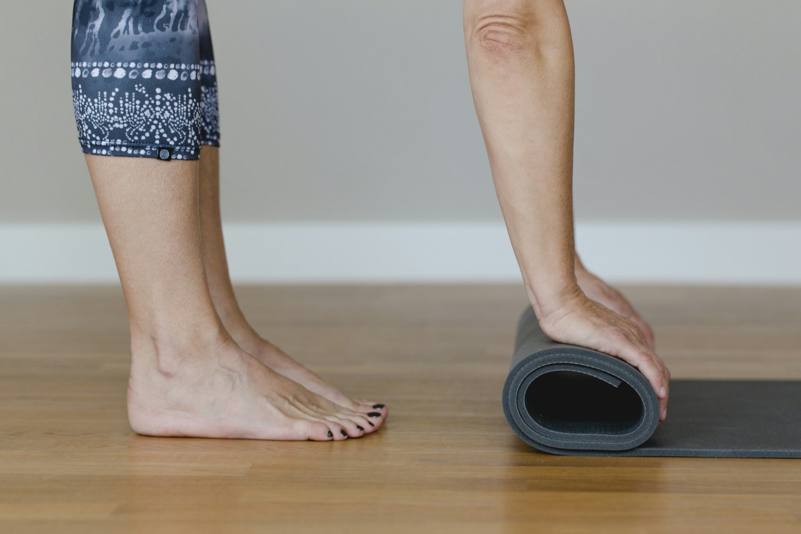 Ahşap zeminde çıplak ayaklar; yanda rulo yapılan bir yoga matı