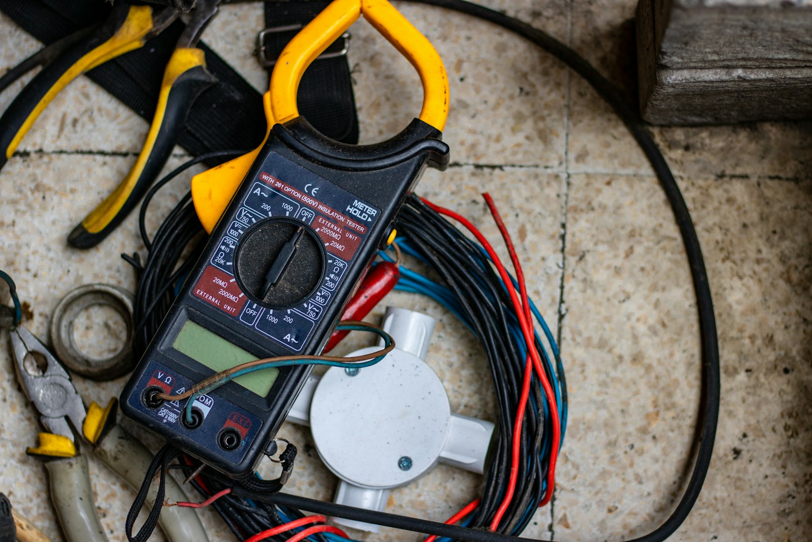 Karolu bir zeminde pens ampermetre, bir kerpeten ve kıvrılmış elektrik kabloları